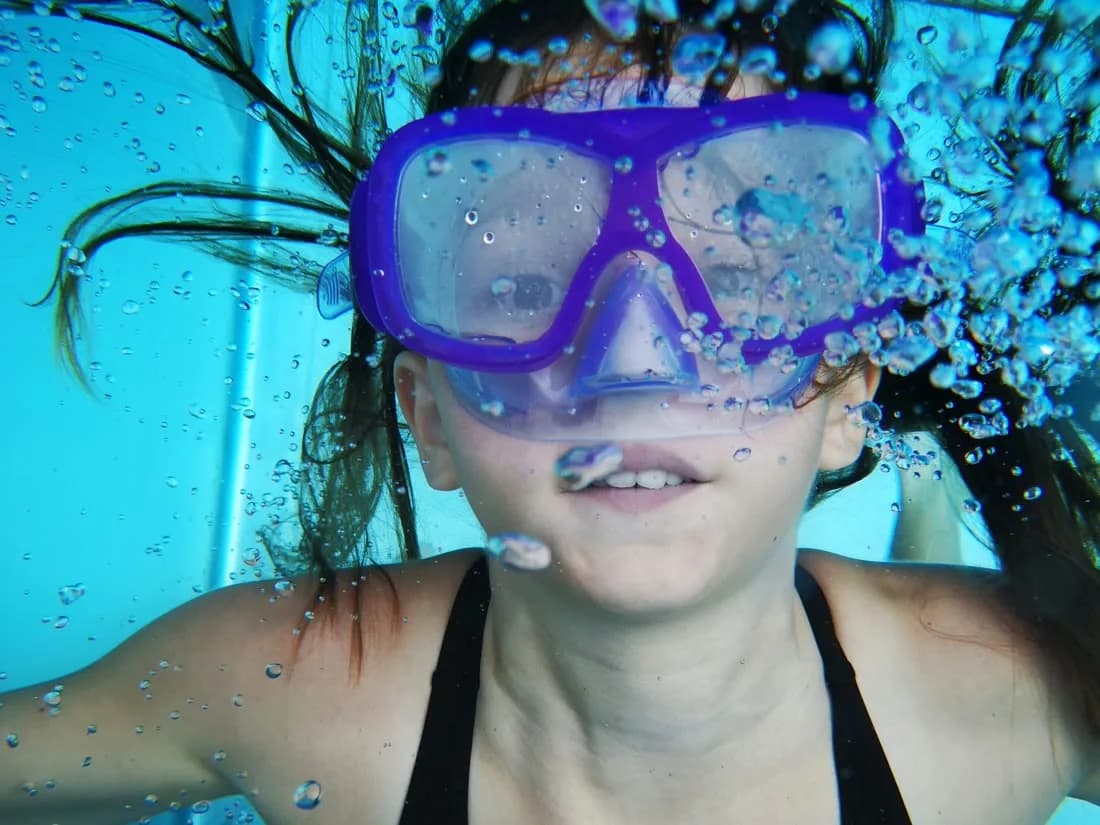 Mädchen mit Tauchmaske unter Wasser im Schwimmbecken